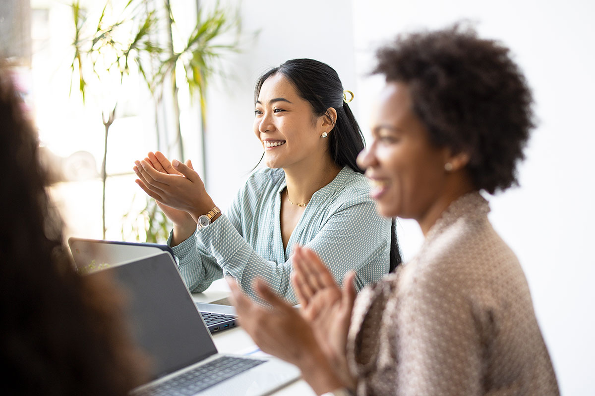 Zwei Kolleginnen lachen am Schreibtisch
